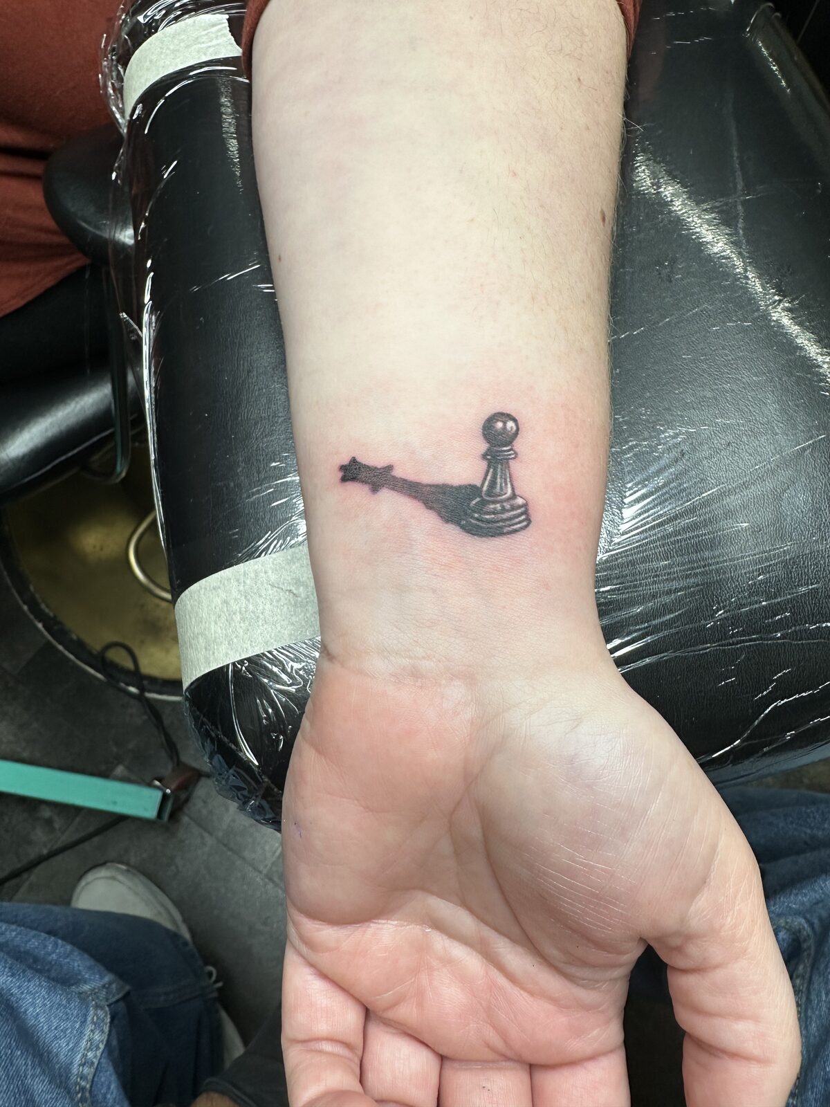 Small black and gray chess pawn with a shooting star tattoo on an inner wrist