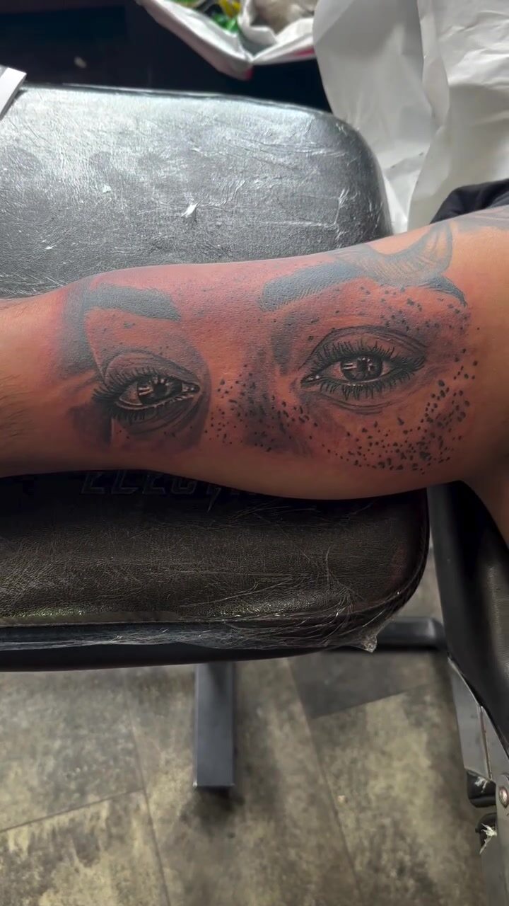 Black and gray realistic eyes tattoo on a forearm