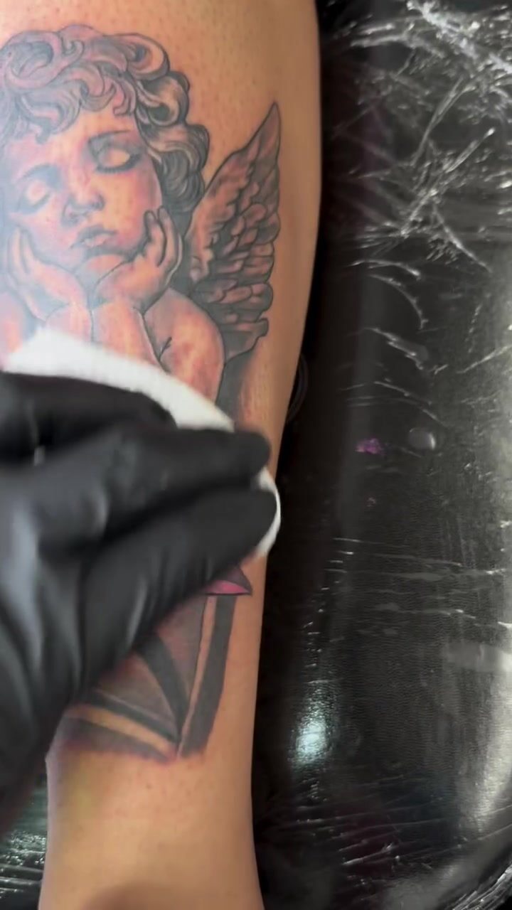 Black and gray cherub tattoo being cleaned after the session