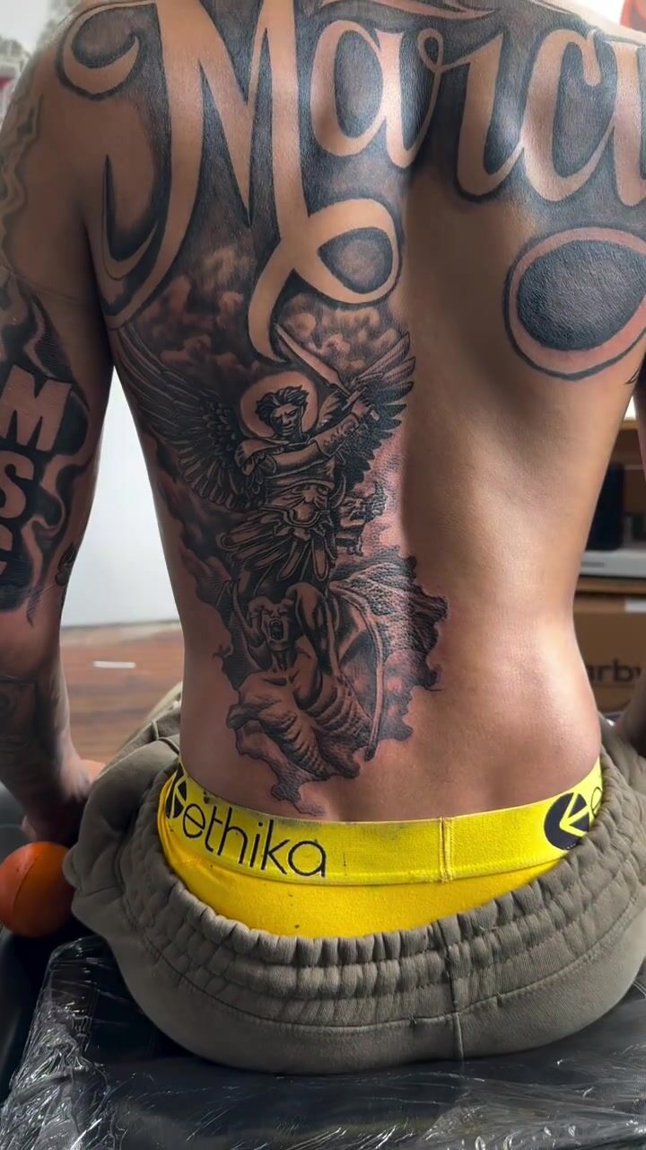 Black and gray archangel back piece tattoo with script lettering