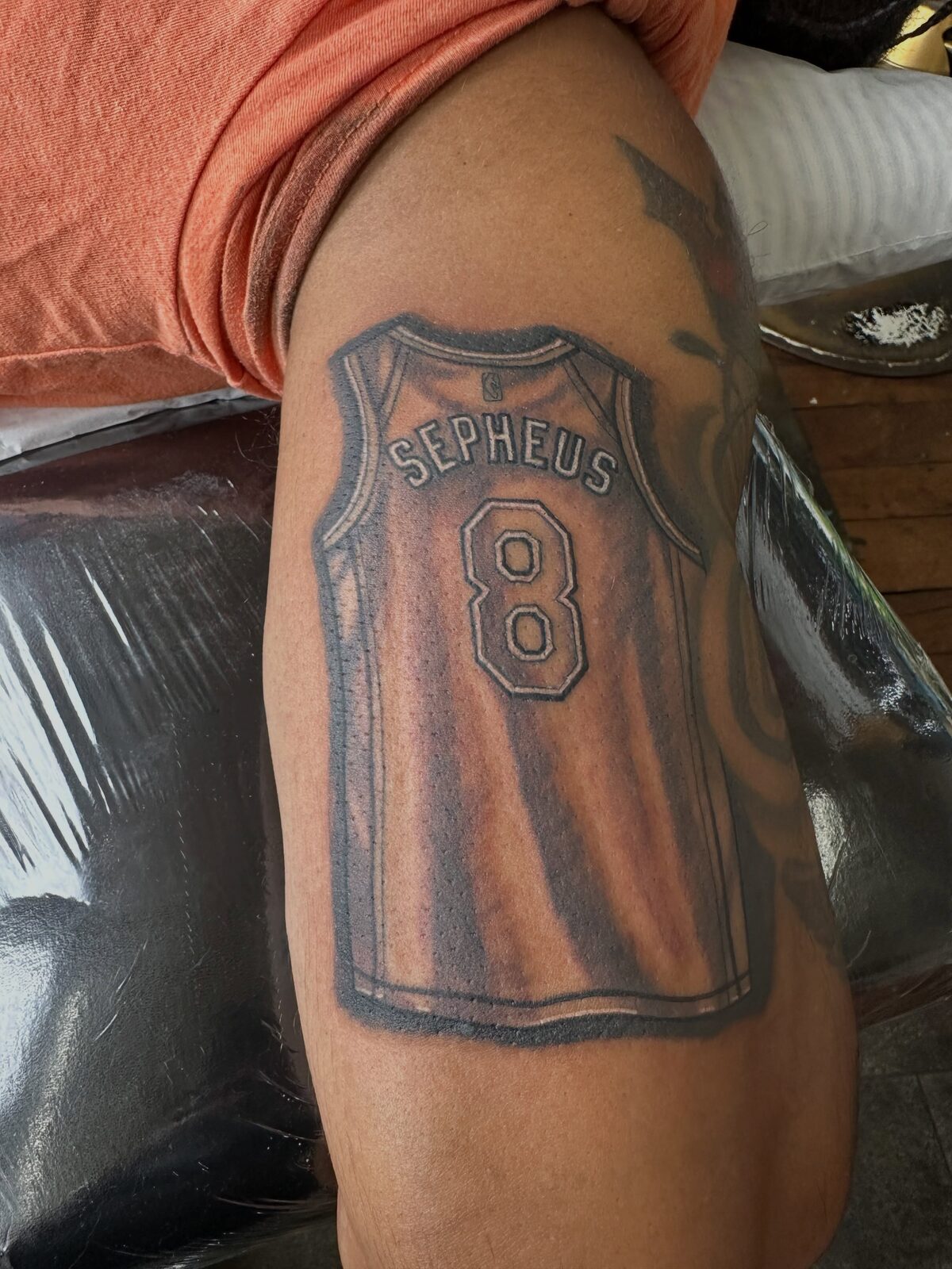 Black and gray number 8 basketball jersey tattoo on an arm