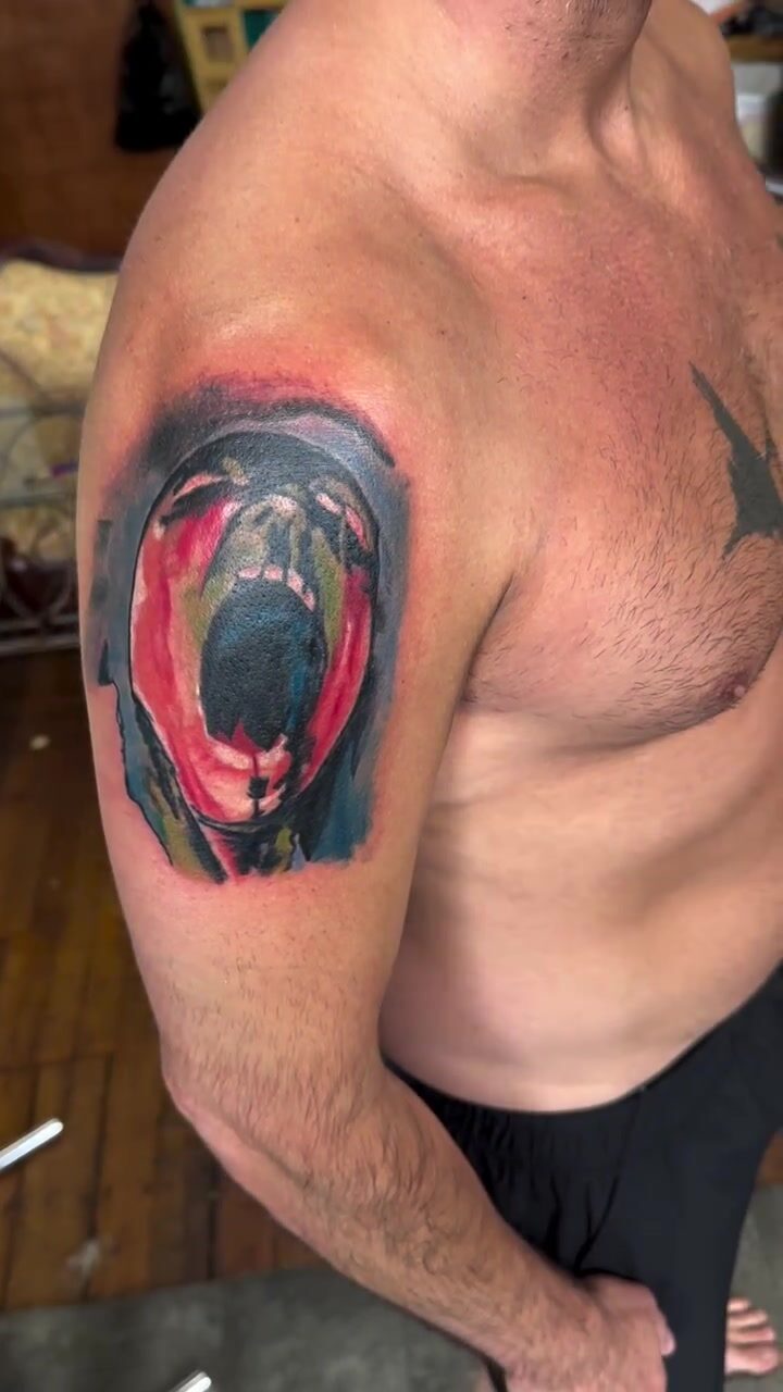 Color screaming face tattoo on a shoulder