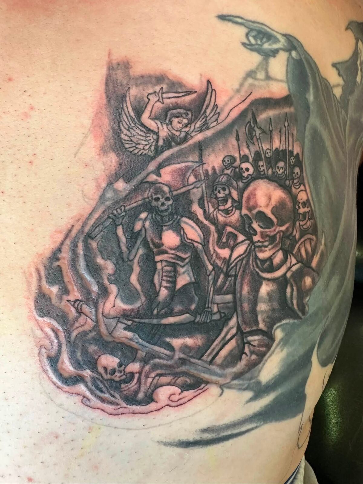 Black and gray skeleton army battle scene with an angel tattoo on the ribs